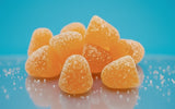 Protein Candy with a liquid center bursting with juicy flavor, shown in a pile on a reflective surface.